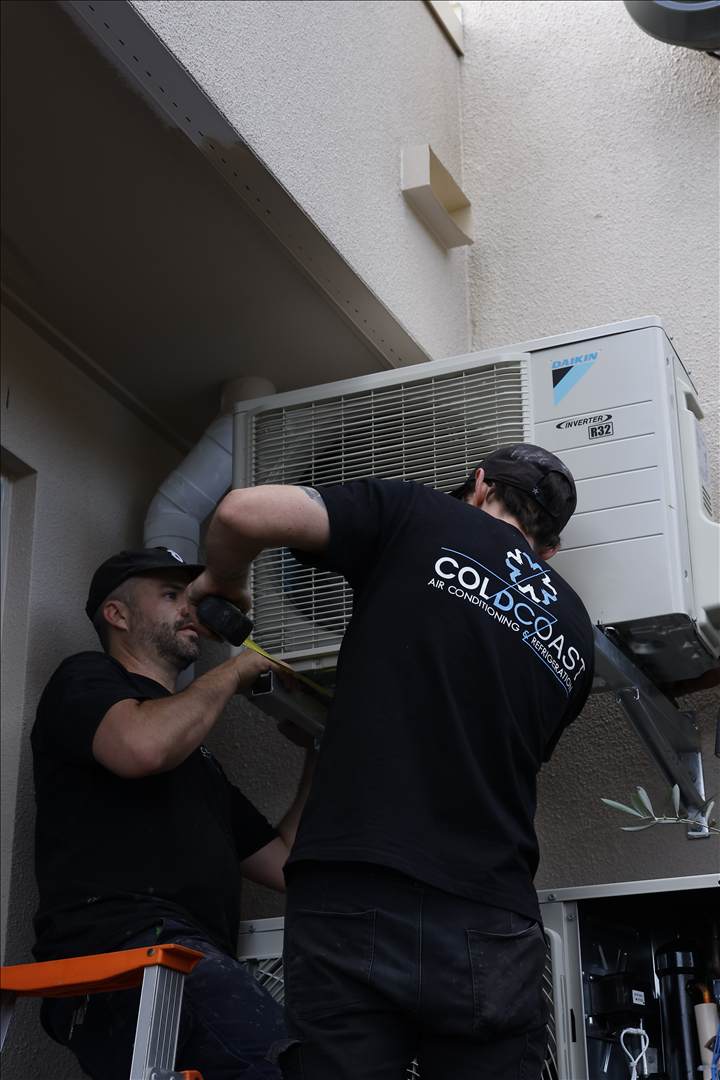 Two COLDCOAST technicians installing a Daikin outdoor unit.